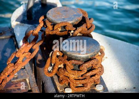 Vecchia catena di ancoraggio abbandonata con ruggine e tassello di ferro, falegname su un palo in un molo marittimo locale in Italia Foto Stock