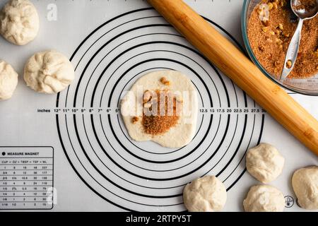 Preparazione delle frittelle coreane dolci Hotteok: Impasto arrotolato riempito con zucchero di canna e noce su una superficie di lavoro in silicone Foto Stock