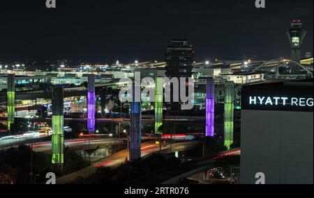 Aeroporto internazionale di Los Angeles, scena notturna, guardando a ovest. I piloni luminosi cinetici gateway di LAX sono mostrati in primo piano. Foto Stock