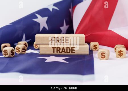 Economia e finanza. Sulla bandiera degli Stati Uniti giacciono cubetti con il simbolo del dollaro e stampi di legno con l'iscrizione - libero scambio. Foto Stock