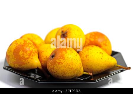 Pere mature su un piatto nero su sfondo bianco Foto Stock