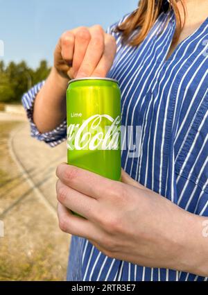 Mani che aprono la lattina di Coca Cola drink, stagno con gusto di lime Foto Stock
