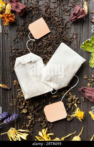 Composizione di tè nero e verde secco, bustine di tè e hibiscus secco, calendula, fiori di lavanda su uno sfondo di legno scuro vista dall'alto. Foto Stock