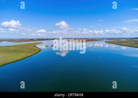 Vista aerea con droni della foce del fiume Tinto. Estuario del Rio Tinto nelle paludi di Huelva con un bel riflesso del cielo Foto Stock