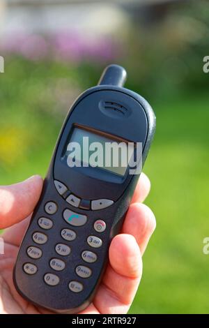 Un vecchio telefono cellulare a pulsante in una mano Foto Stock