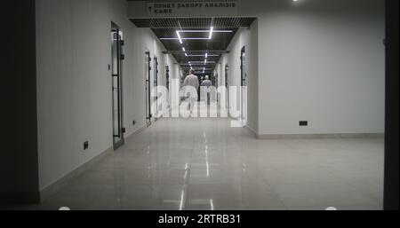 Medici, operatori sanitari e pazienti camminano lungo il luminoso corridoio della clinica. Personale medico e persone in ospedale privato o moderno centro medico. Laboratorio o stazione di emergenza. Vista posteriore. Foto Stock