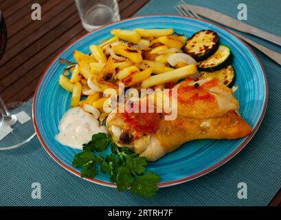 Cosce di pollo al forno con patate e zucchine al piatto Foto Stock