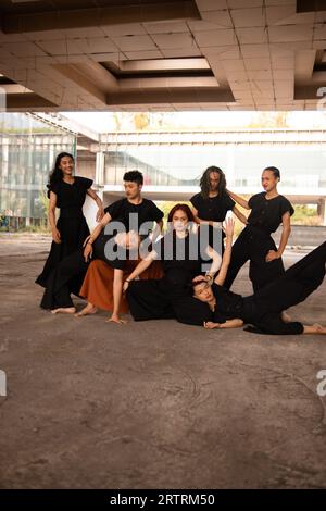 Un gruppo di uomini asiatici che si posa allegramente con i loro amici indossando il nero in un vecchio edificio Foto Stock