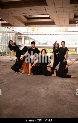 Un gruppo di uomini asiatici che si posa allegramente con i loro amici indossando il nero in un vecchio edificio Foto Stock