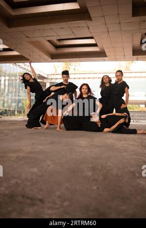 Un gruppo di uomini asiatici che si posa allegramente con i loro amici indossando il nero in un vecchio edificio Foto Stock