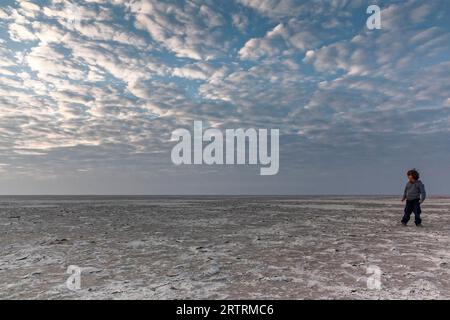 Ragazzo che corre attraverso il deserto di sale, la salina Makgadikgadi, il Botswana Foto Stock