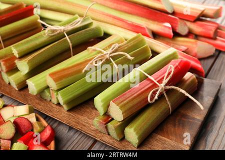 Molti steli di rabarbaro tagliati su un tavolo di legno, primo piano Foto Stock