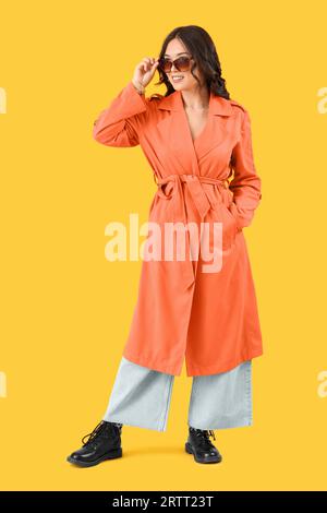 Elegante giovane donna asiatica in abiti autunnali su sfondo giallo Foto Stock