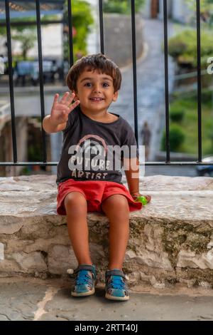 Ritratto di un bambino di due anni seduto molto allegro che si gode le vacanze estive Foto Stock