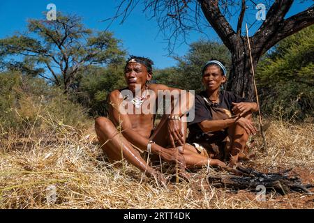 Bushman e San Woman stanno facendo fuoco a Kalahari, Botswana Foto Stock