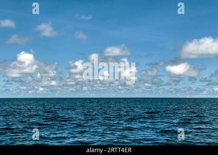 Foto con saturazione leggermente ridotta ha cambiato tonalità di nuvole Altocumulus riflessa di fronte al cielo blu all'orizzonte sopra l'oceano Pacifico ancora senza Foto Stock