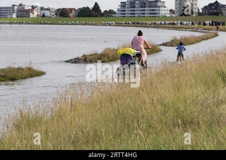 Ciclista su un sentiero inondato con l'alta marea sulla spiaggia di Cuxhaven, costa del Mare del Nord, bassa Sassonia, Germania Foto Stock