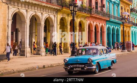 L'Avana, Cuba il 22 dicembre 2015: Un taxi blu oldtimer attraversa l'Habana Vieja di fronte a una facciata colorata Foto Stock