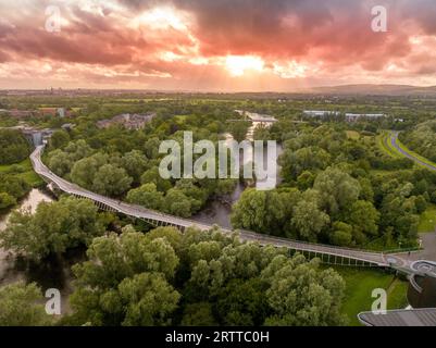 Vista panoramica aerea del Living Bridge, moderna traversata pedonale curva sul fiume Shannon presso l'Università di Limerick con un tramonto mozzafiato Foto Stock
