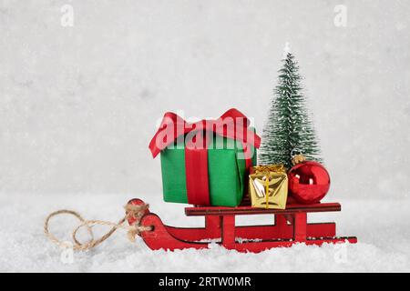 Slitta in miniatura con regali di Natale, ornamenti e albero di Natale. Buon Natale e buon anno nuovo biglietto d'auguri. Foto Stock