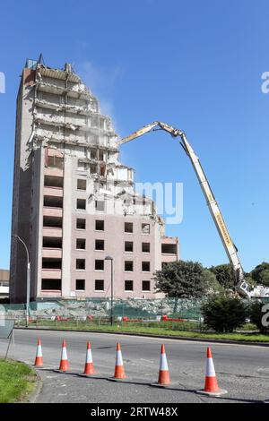 Alto blocco di appartamenti, Irvine, Ayrshire, Scozia, Regno Unito, essere demolito da una gru meccanica. Foto Stock