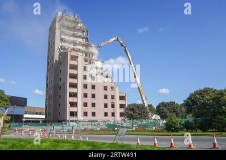 Alto blocco di appartamenti, Irvine, Ayrshire, Scozia, Regno Unito, essere demolito da una gru meccanica. Foto Stock