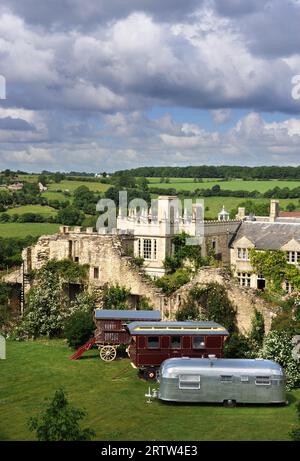 Tre generazioni di roulotte, tra cui un vagone in stile zingaro o romeno e una carovana US Airstream in una casa di campagna del Wiltshire, Regno Unito. Foto Stock