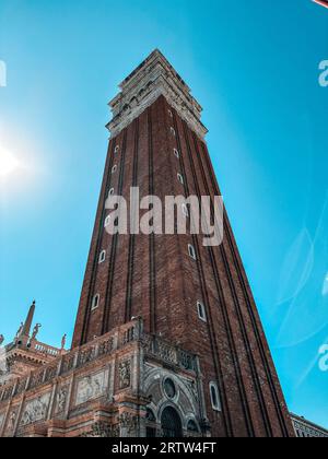 Un edificio maestoso con una torre dell'orologio alta contro un vibrante cielo blu, la sua facciata illuminata al sole Foto Stock