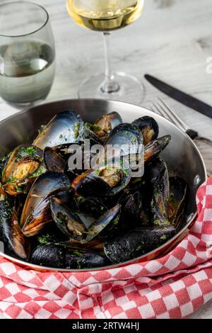 Cozze blu al forno in speziato al limone in una pentola nera in ghisa Foto Stock