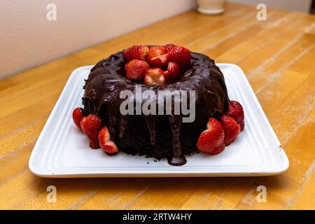 Una torta al cioccolato con glassa al cioccolato decorata con fragole fresche Foto Stock