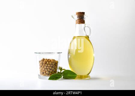 Olio di soia e semi di soia secchi in contenitore di vetro e lascia uno sfondo bianco isolato. Vista font. Foto Stock