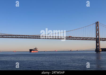 Vista del Bay Bridge contro il cielo blu al tramonto, San Francisco, California, Stati Uniti, USA. Immagine acquisita con la spedizione sullo sfondo. Foto Stock