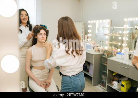 Riflesso che riflette la creazione di immagini creative per le riprese fotografiche. Makeup artist e parrucchiere donna che si prepara donna a un evento matrimonio o.. Foto Stock