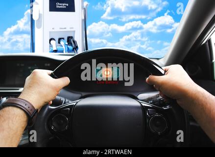 Visualizzazione di avvertenza batteria scarica sullo schermo del quadro strumenti di un'auto elettrica, il segnale di tensione della batteria sta diminuendo e scarica, auto elettrica parcheggiata sul veicolo elettrico Foto Stock