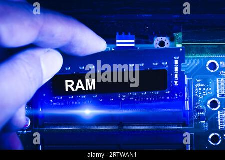 Mano del tecnico inserire la memoria RAM nello slot di memoria della scheda madre del computer. Il tecnico aggiorna la memoria RAM in un notebook. tono blu. Foto Stock