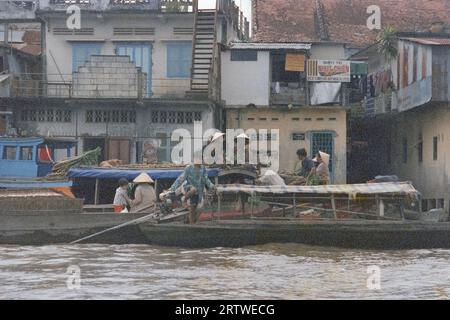 Mercanti vietnamiti che trasportano merci in una barca sul fiume Mekong Foto Stock