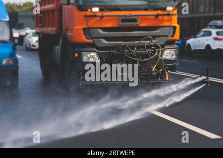 Le macchine municipali per camion irrigano l'asfalto, il processo di disinfezione stradale e la pulizia da polvere e sporco, pulendo le macchine spazzatrici a flussatore wa Foto Stock