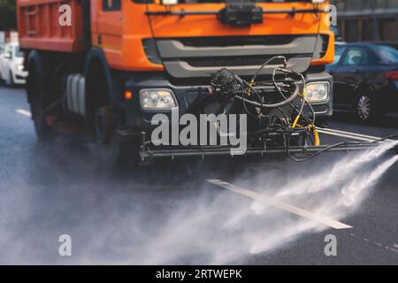 Le macchine municipali per camion irrigano l'asfalto, il processo di disinfezione stradale e la pulizia da polvere e sporco, pulendo le macchine spazzatrici a flussatore wa Foto Stock