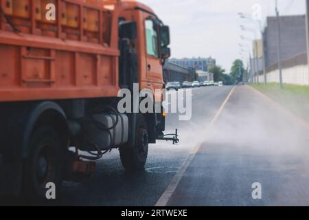 Le macchine municipali per camion irrigano l'asfalto, il processo di disinfezione stradale e la pulizia da polvere e sporco, pulendo le macchine spazzatrici a flussatore wa Foto Stock