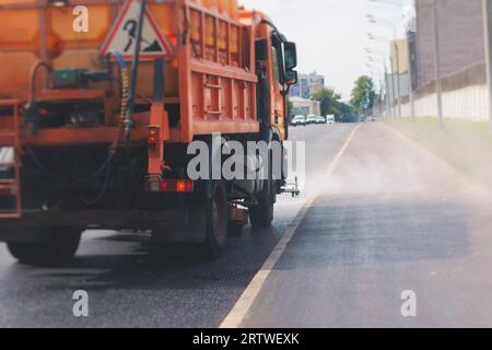 Le macchine municipali per camion irrigano l'asfalto, il processo di disinfezione stradale e la pulizia da polvere e sporco, pulendo le macchine spazzatrici a flussatore wa Foto Stock