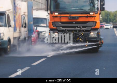 Le macchine municipali per camion irrigano l'asfalto, il processo di disinfezione stradale e la pulizia da polvere e sporco, pulendo le macchine spazzatrici a flussatore wa Foto Stock