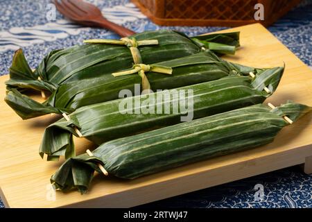 Lemper Ayam intero avvolto in foglie di banana, uno spuntino salato indonesiano a base di riso glutinoso ripieno di pollo sminuzzato condito da vicino Foto Stock