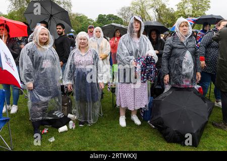 Una grande folla che sfiora la pioggia per guardare l'incoronazione di re Carlo III, su un gigantesco schermo TV. Hyde Park, Londra, Regno Unito. 6 maggio 2023 Foto Stock