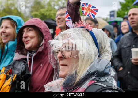 Una grande folla che sfiora la pioggia per guardare l'incoronazione di re Carlo III, su un gigantesco schermo TV. Hyde Park, Londra, Regno Unito. 6 maggio 2023 Foto Stock