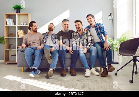 Amici felici, allegri e sorridenti o padre e figli adulti seduti sul divano a casa Foto Stock