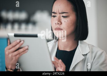 Tablet, farmacia e donna asiatica confusa in laboratorio per sito web, app benessere e telesalute. Assistenza sanitaria, farmaceutica e lavoratori in digitale Foto Stock