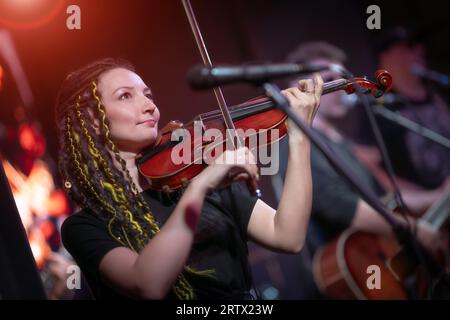 Una violinista femminile suona il violino. La band si esibisce sul palco, concerto di musica rock. Foto Stock