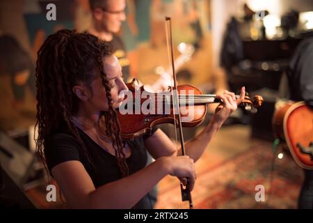 Una violinista femminile suona il violino. La band si esibisce sul palco, concerto di musica rock. Foto Stock