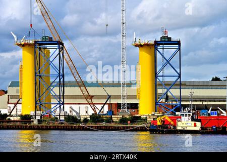 Produzione di nuove turbine eoliche giganti presso lo Smulders Howdon nel cantiere Tyne contro il cielo nuvoloso che mostra torri di supporto e il BOABARGE 66 Foto Stock