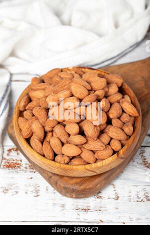Mandorla in ciotola di legno. Mandorle arrostite su fondo di legno bianco Foto Stock